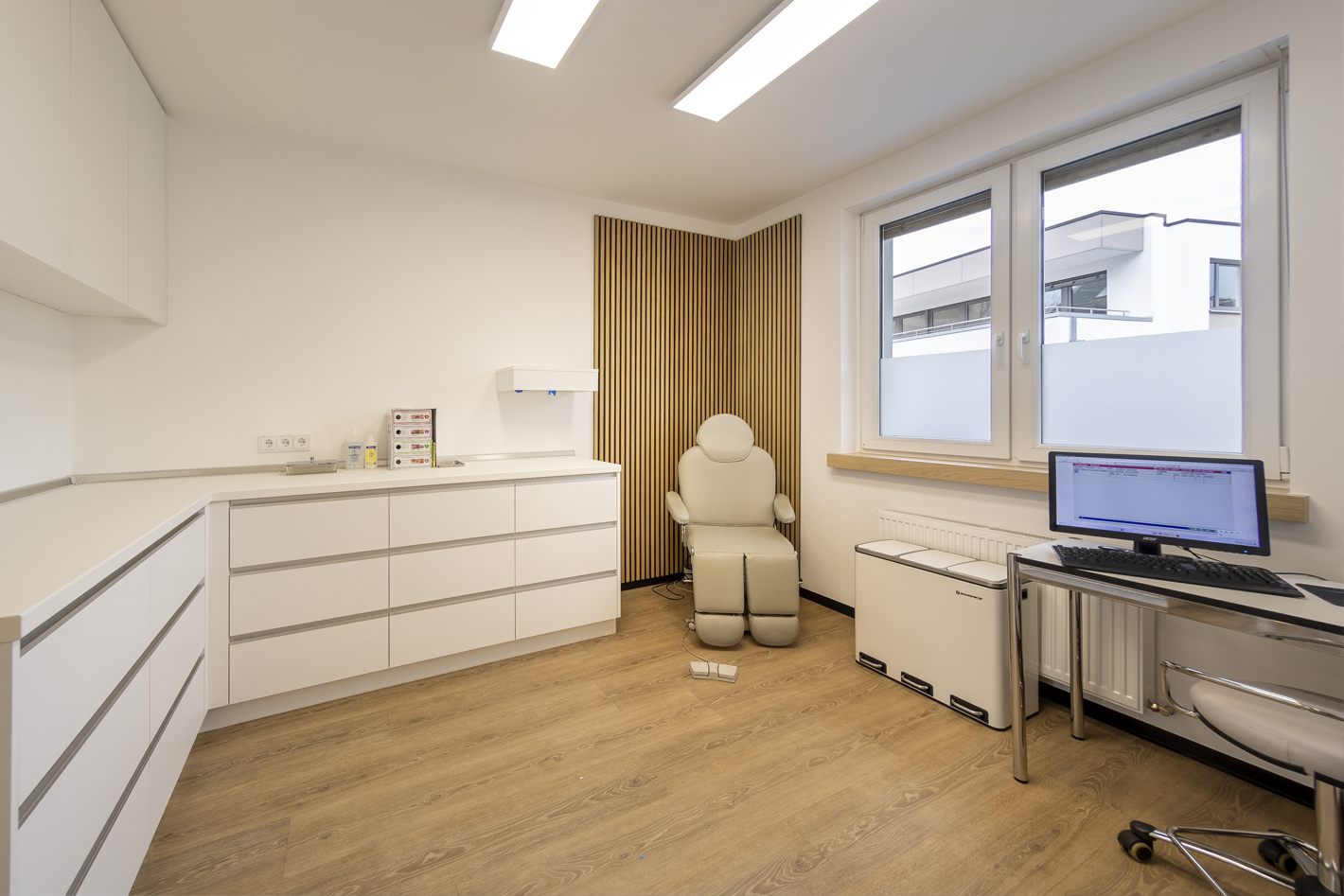 Behandlungszimmer mit Behandlungsstuhl und großen Fenstern